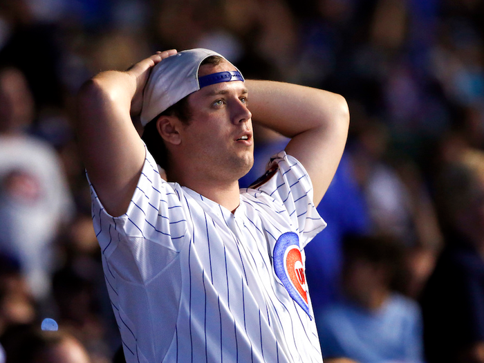 Cubs fan in a pinstriped jersey holds his hands behind his head.